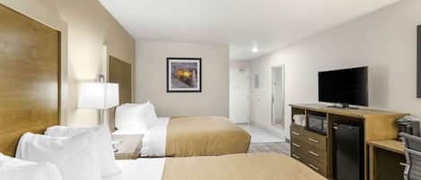 A hotel room with two beds, a desk with a TV, a microwave, and a refrigerator.