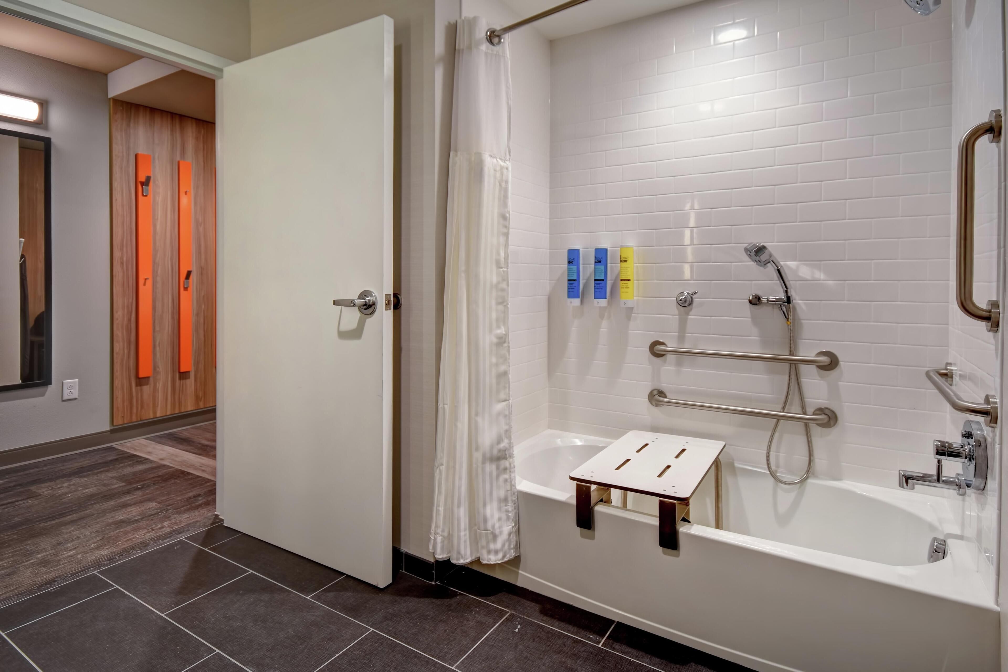 A modern bathroom with a white bathtub, shower, and a small step stool.