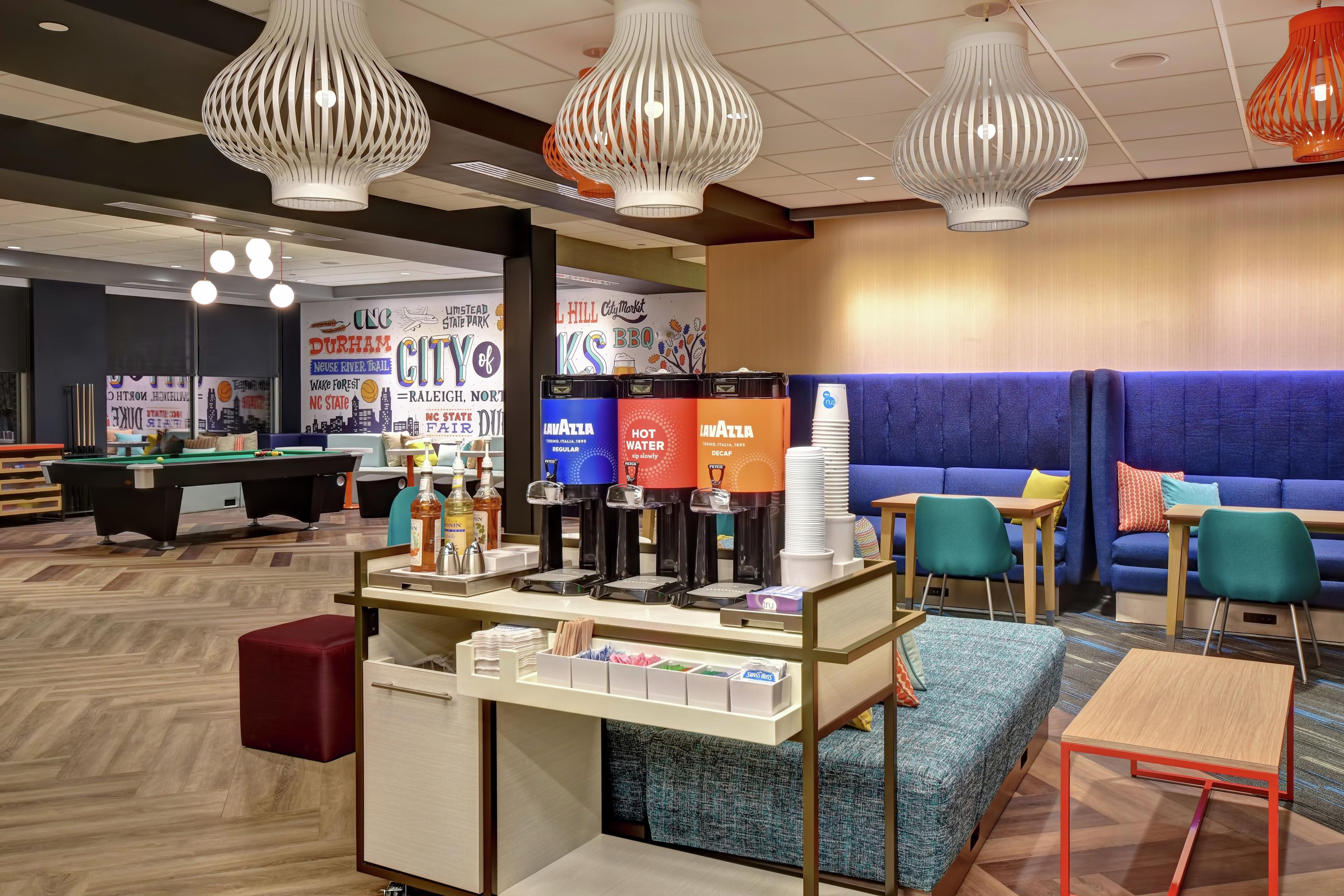 A modern lounge area with a pool table, seating, and beverage dispensers.