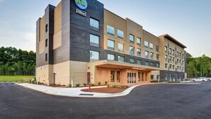 A modern hotel building with a prominent 'tru' logo, a brick facade, and a well-maintained entrance area. - Tru by Hilton Raleigh Durham Airport (Morrisville)