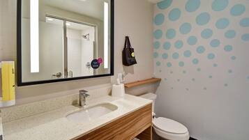Un baño con lavamanos, espejo, inodoro y una pared con lunares azules.