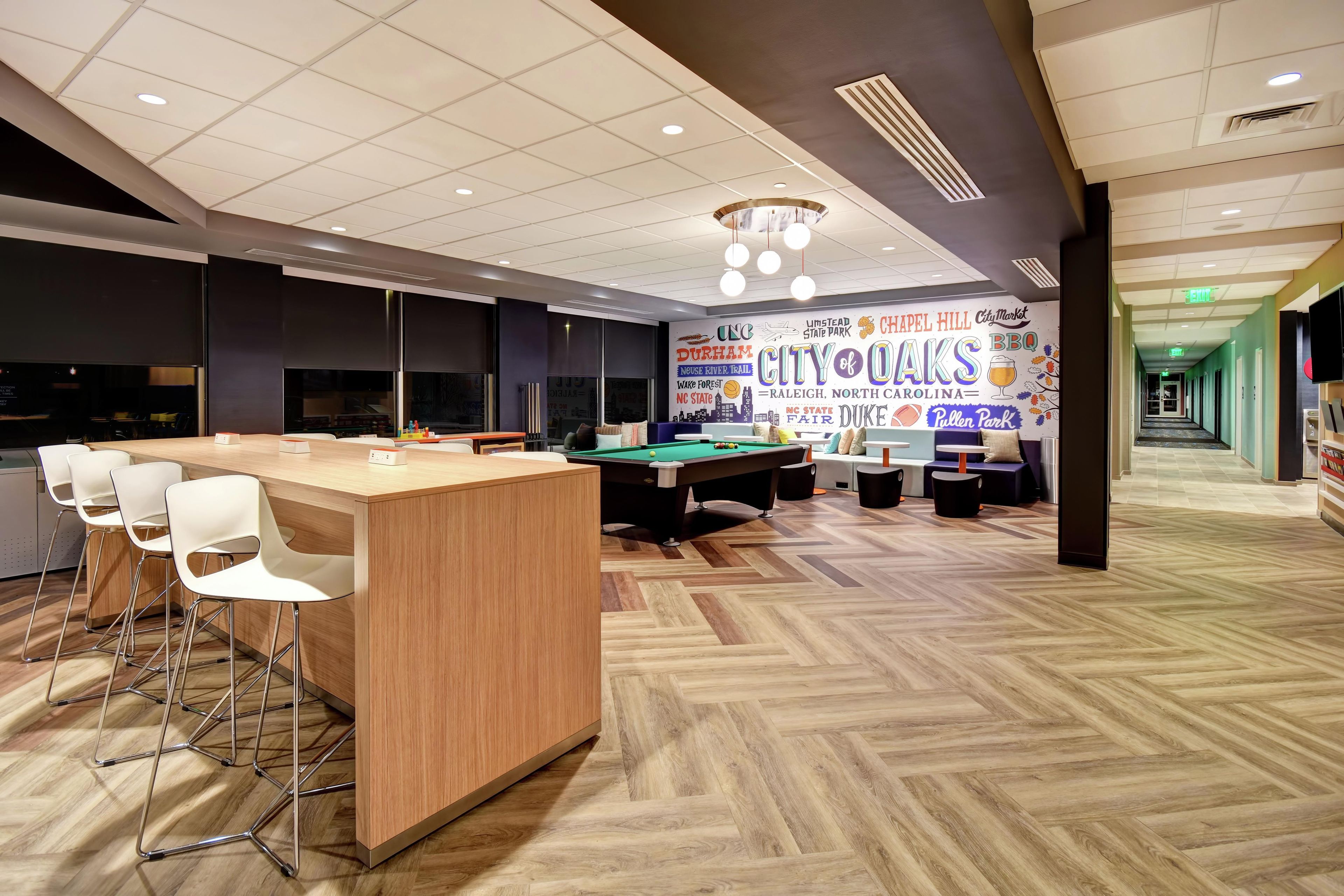 A modern lounge area with a pool table, bar, and seating.
