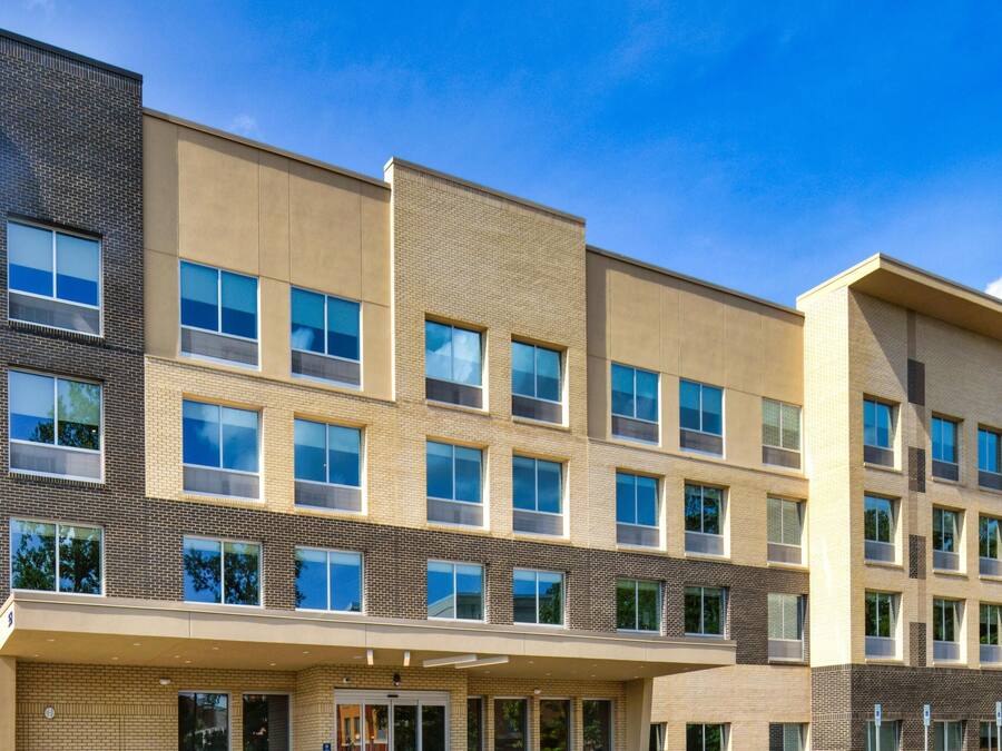 A multi-story hotel with a Hilton logo, a covered entrance, and a clear blue sky.