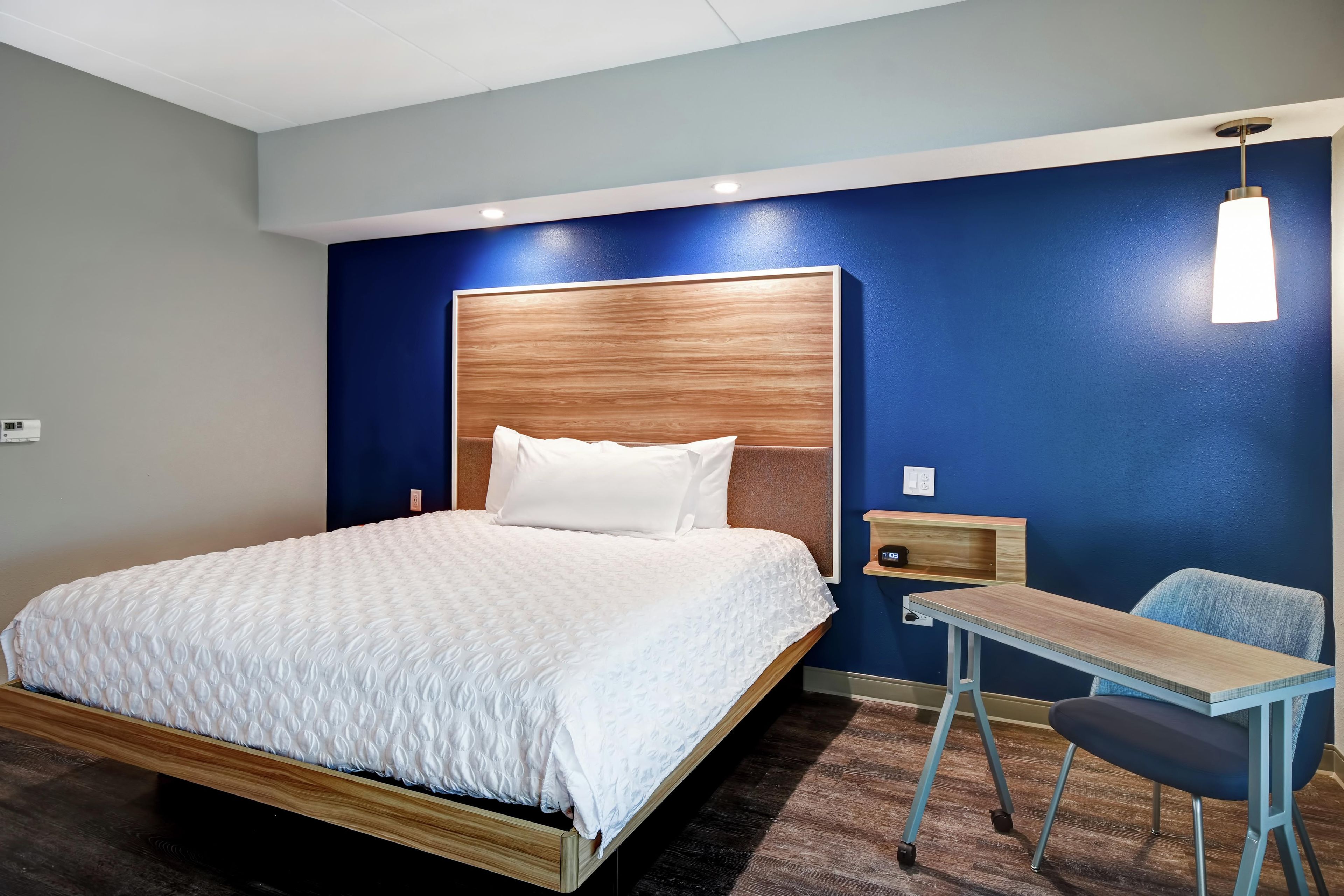 Una habitació d'hotel amb un llit, un escriptori i una cadira.