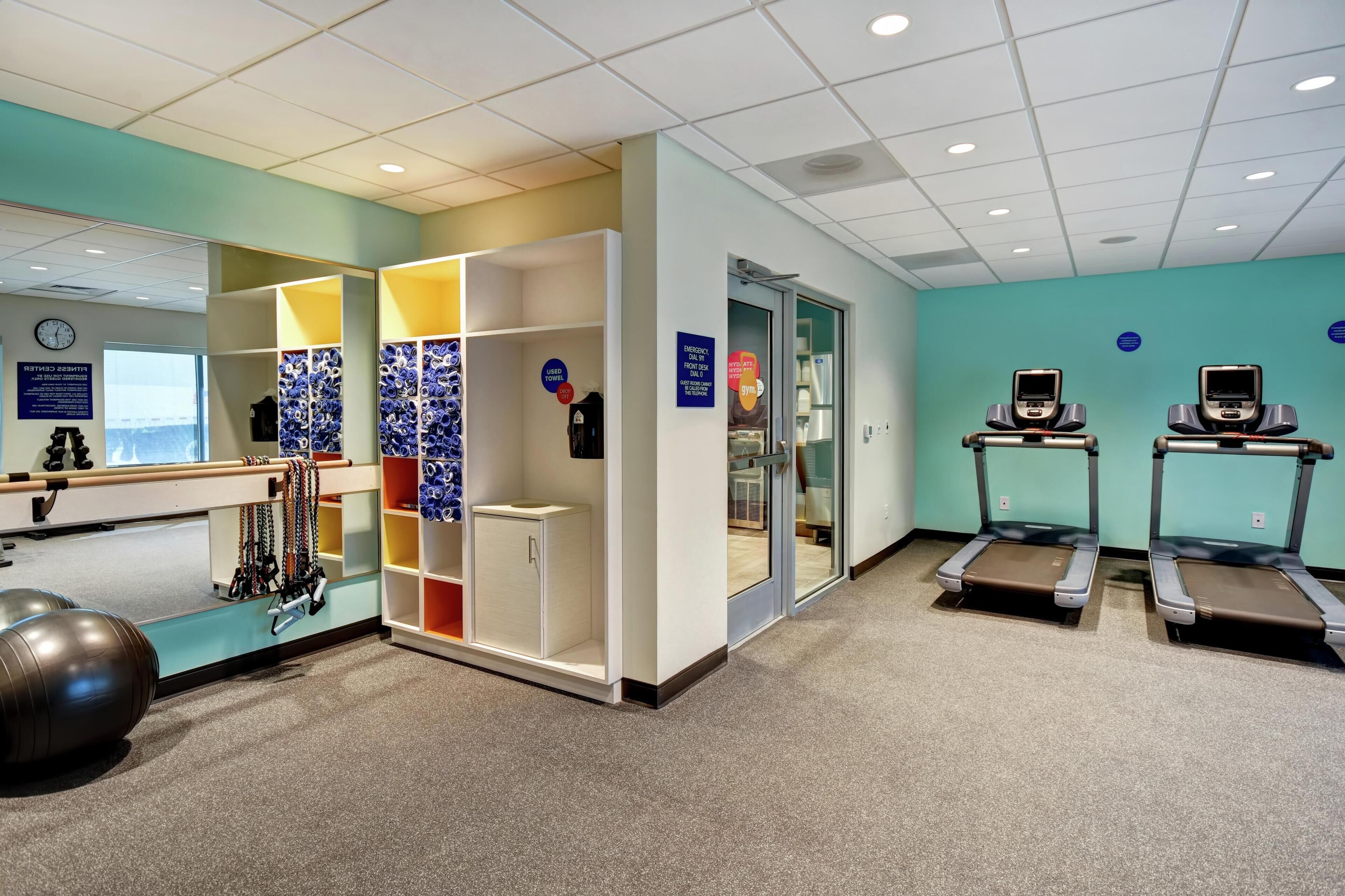 A fitness center with exercise equipment, a treadmill, and a mirrored wall.