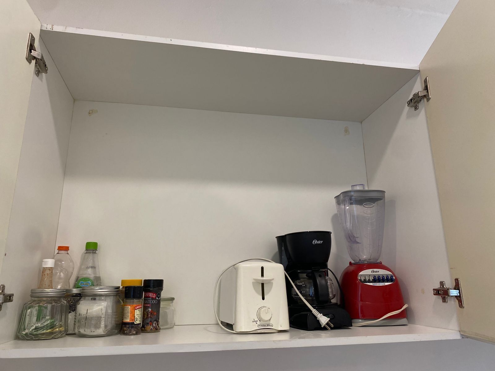 Un pensile da cucina con un tostapane, una macchina da caffè, un frullatore e diversi barattoli di spezie.