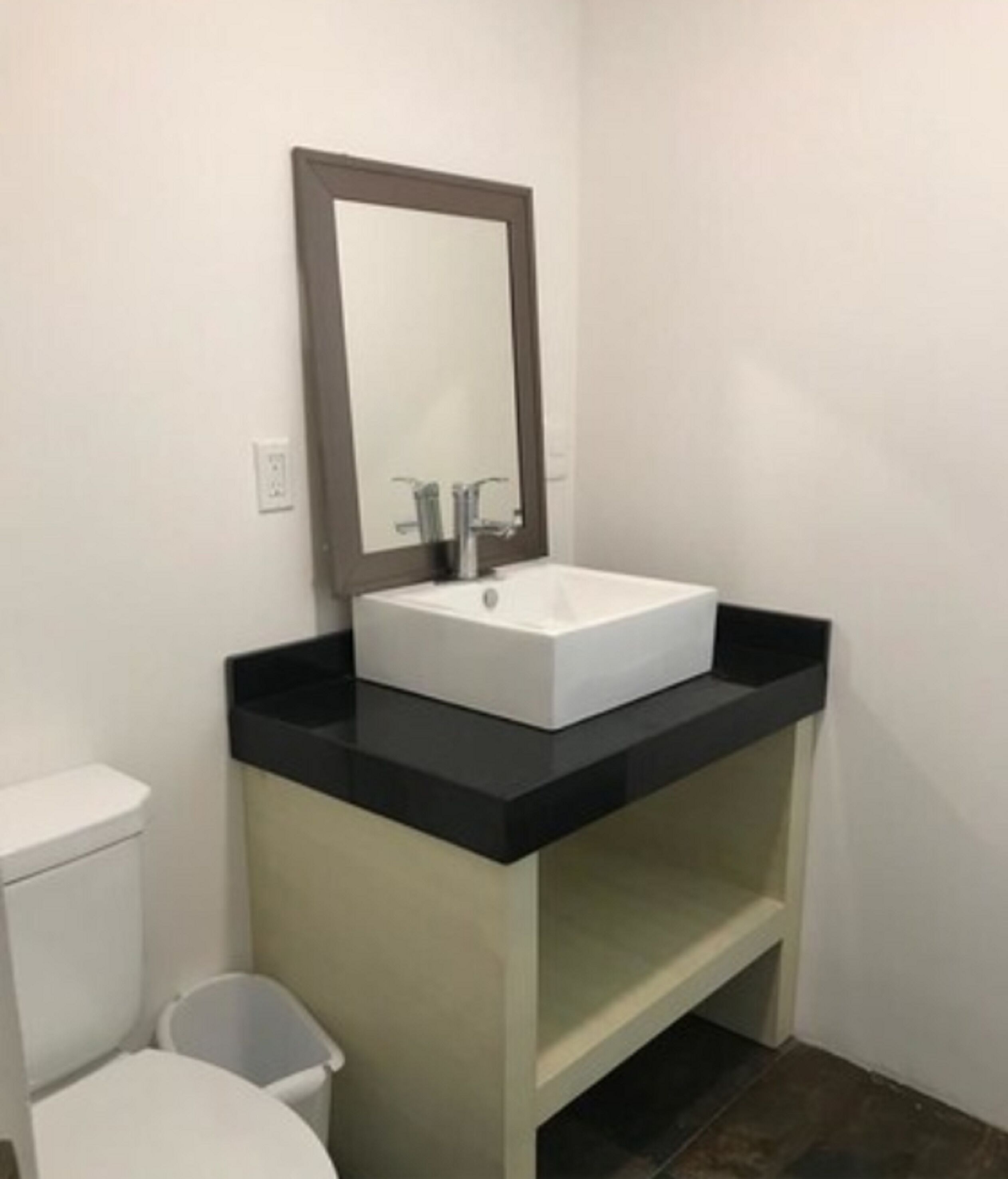 Une petite salle de bain avec un lavabo blanc, un miroir et des toilettes.