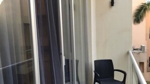 A balcony with a glass door, a chair, and a small table. - Estudio cerca del mar, en Puerto Aventuras 201 (Puerto Aventuras)