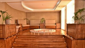 Een ruime kamer met een houten vloer, een rond zitgedeelte en een groot raam dat natuurlijk licht binnenlaat.