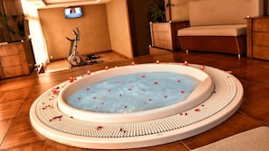 Een spa-ruimte met een jacuzzi, fitnessapparatuur en een televisie.