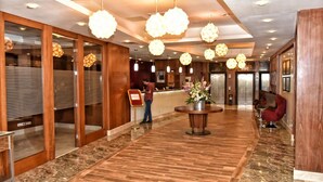Een hotelhal met houten vloeren, een receptiebalie en een rode stoel.