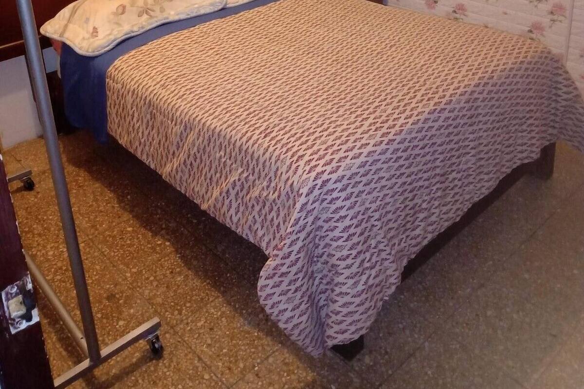 Ein Schlafzimmer mit einem hölzernen Bett, einer Wand mit Blumenmuster und einem kleinen Nachttisch.