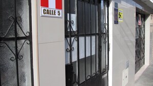 A building facade with a metal gate, a sign reading "CALLE 5", and a "BUZON" sign. - HOSPEDERIA Calle 5 (Callao)