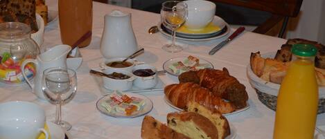 A breakfast table with various food items, including bread, pastries, and condiments.
