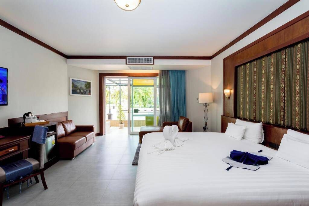 Habitación de hotel con cama, escritorio, silla, televisión y vista al exterior.