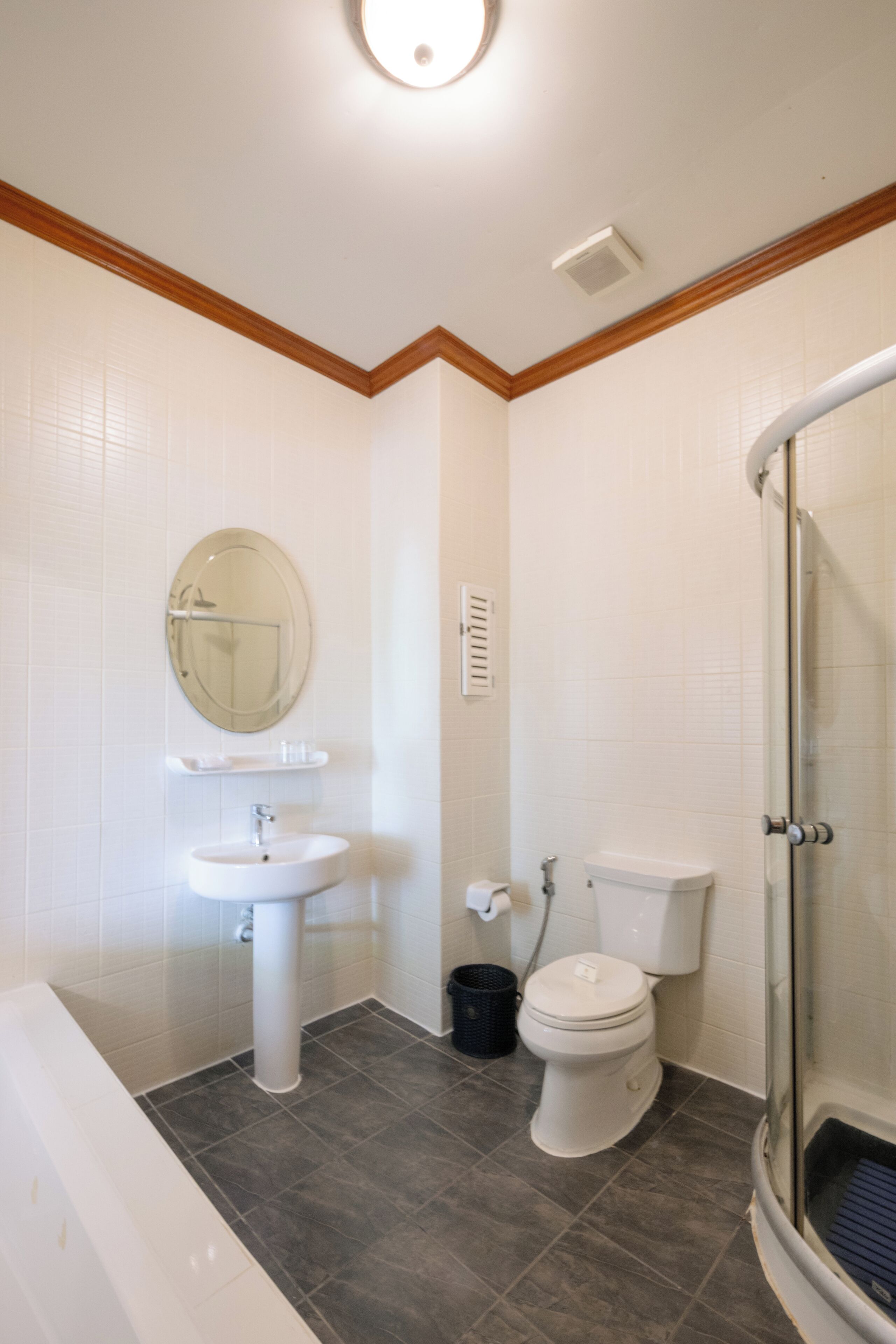 A bathroom with a toilet, sink, mirror, and shower.