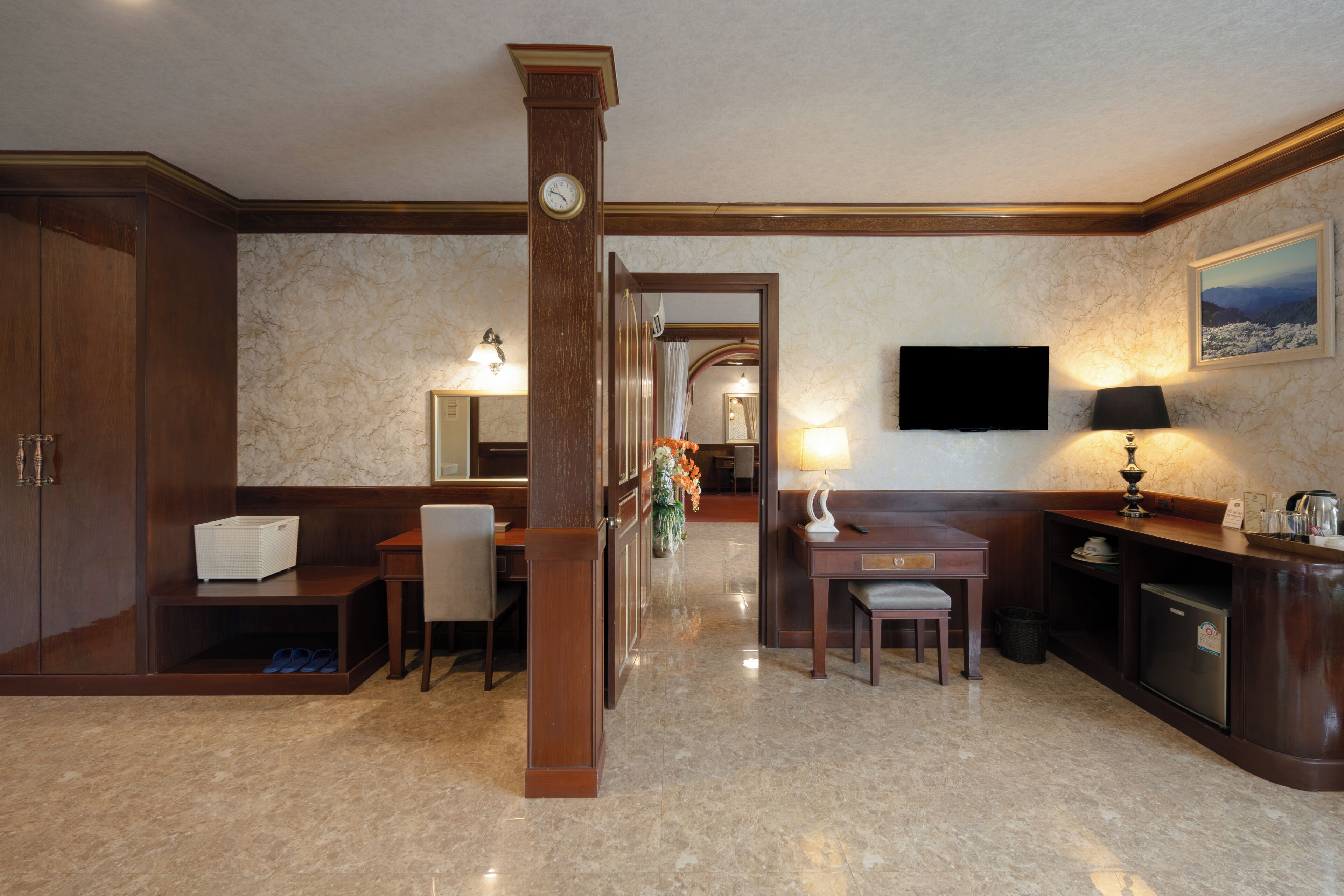 A hotel lobby with a reception desk, seating area, and a large mirror.
