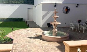 A courtyard with a stone fountain, white outdoor furniture, and a potted plant. - Hotel Casa Cantera (León)