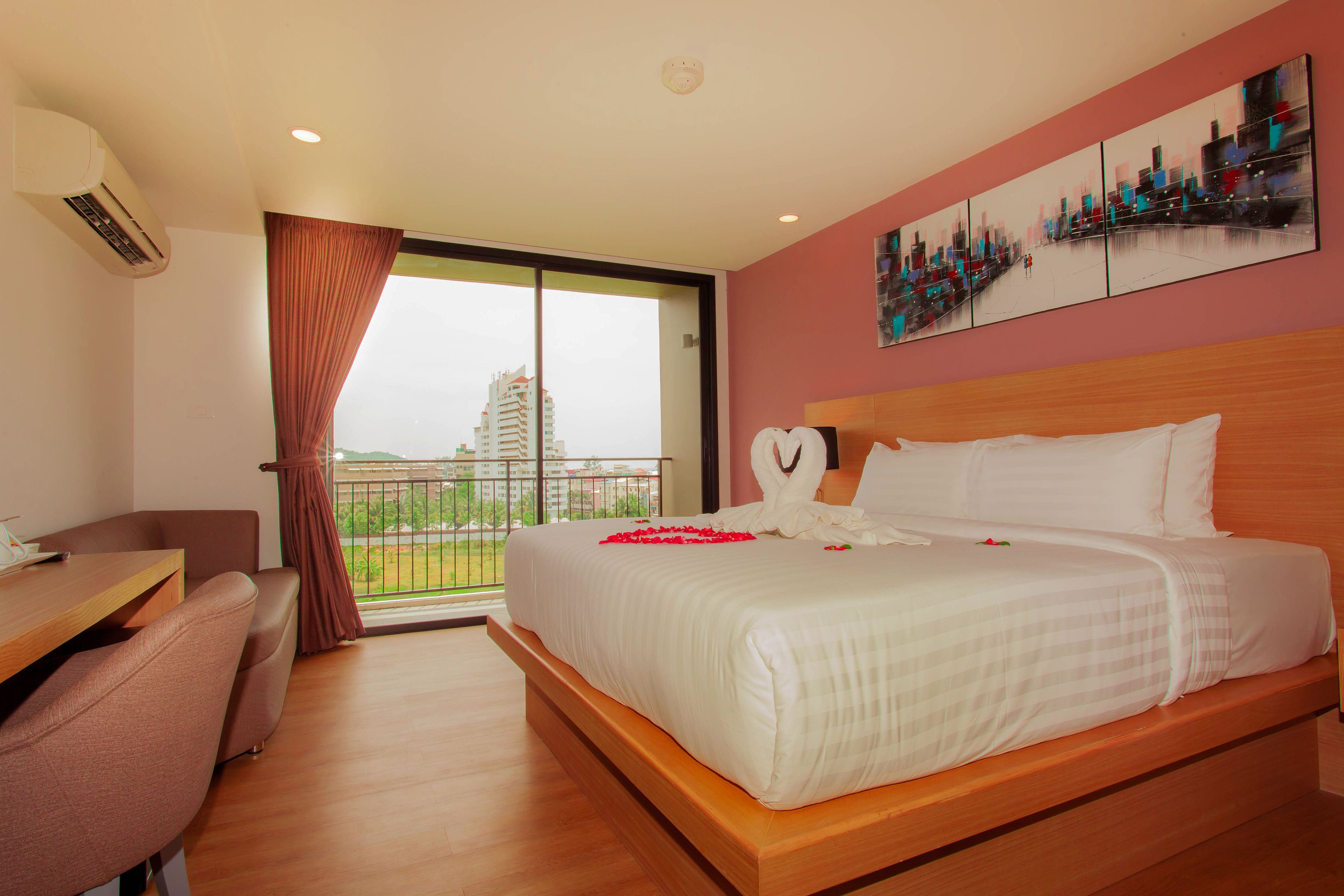 A hotel room with a large bed, a desk, and a view of a cityscape.