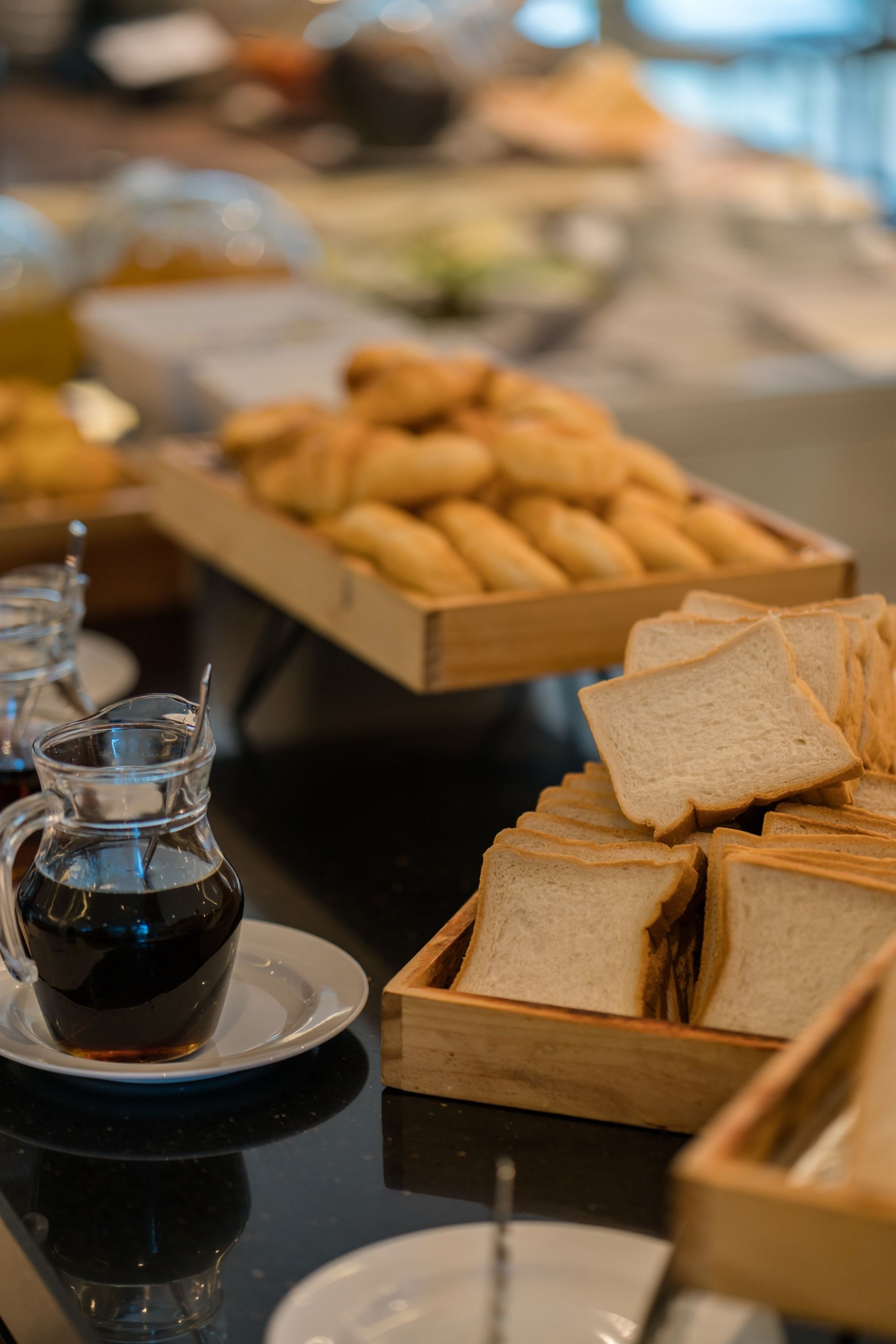 Una mesa de buffet con pan, bollería y una jarra de café.