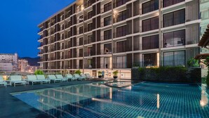 A modern hotel with a rooftop infinity pool, multiple balconies, and lounge chairs. - New Square Patong Hotel (Patong)