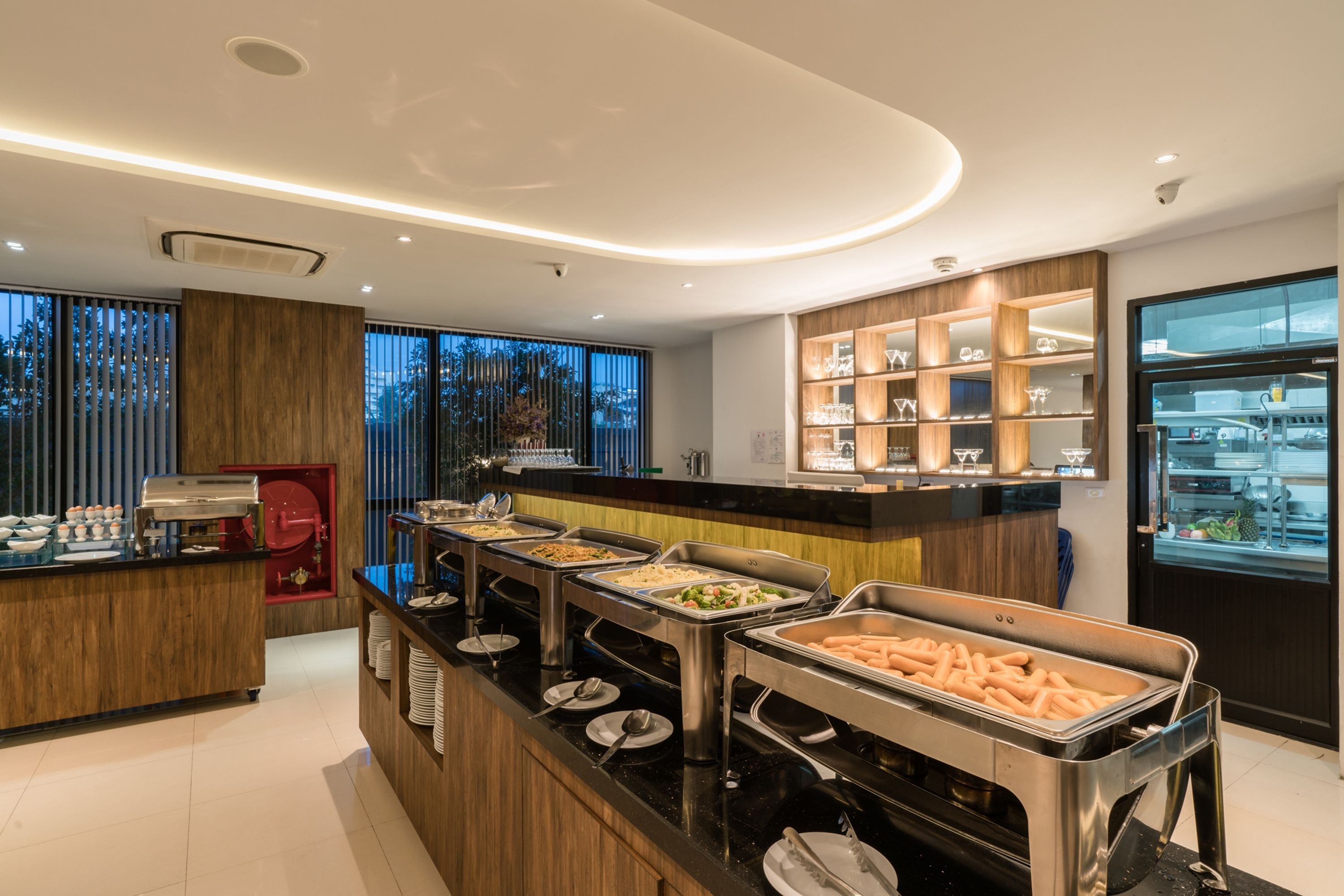 A buffet area with various food stations, a coffee machine, and a display case with glassware.