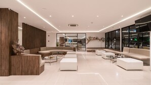 A modern hotel lobby with a reception desk, sofas, and a glass partition. - New Square Patong Hotel (Patong)