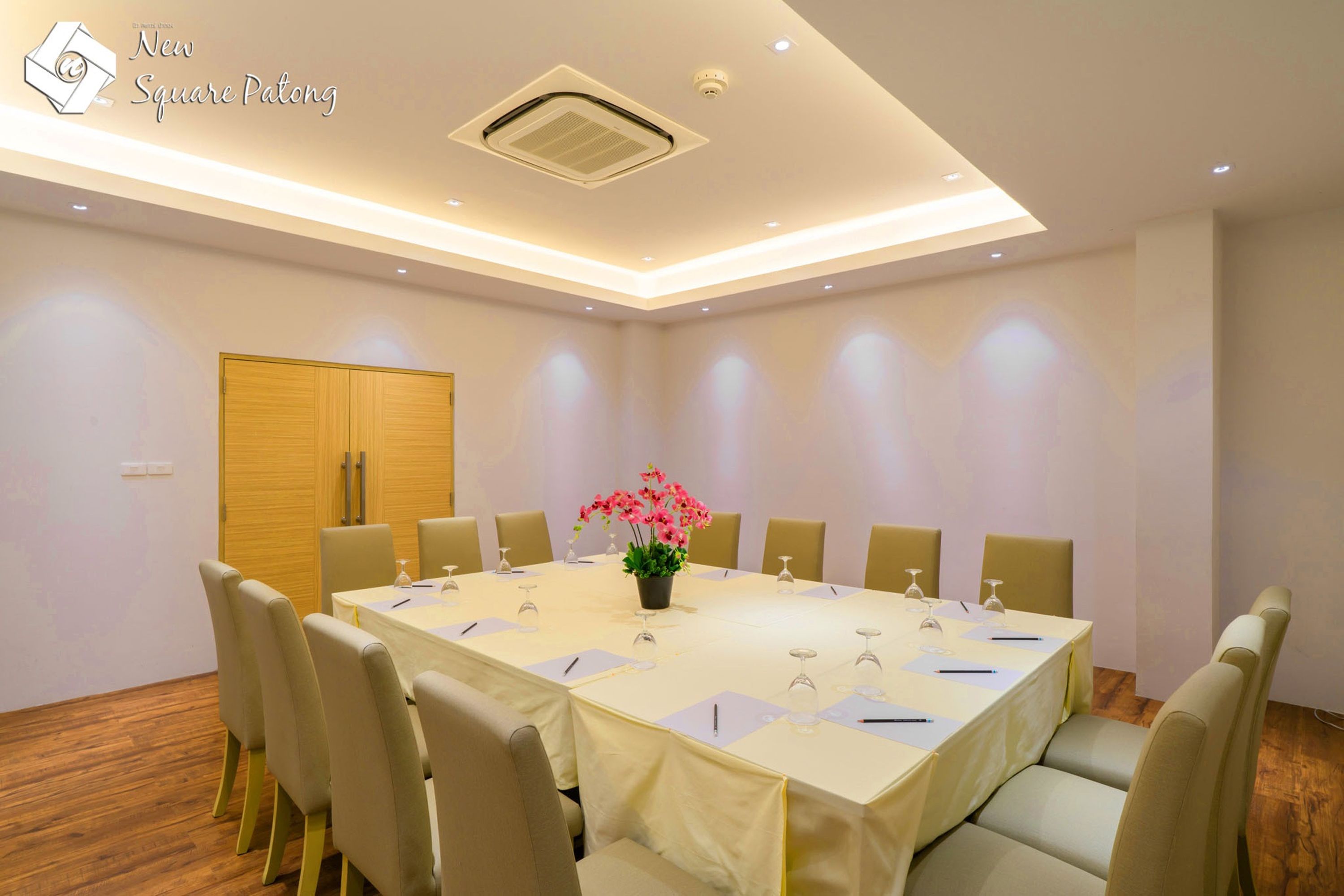 Un salón de conferencias con una larga mesa, sillas, un centro de mesa floral y una puerta de madera.