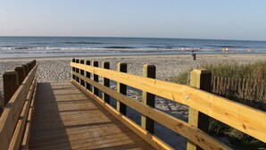 A wooden boardwalk leading to a beach with people in the distance. - 2000sq ft Villa 401, Ocean View steps to the beach, small pool hot tub 4 king bd (North Myrtle Beach)