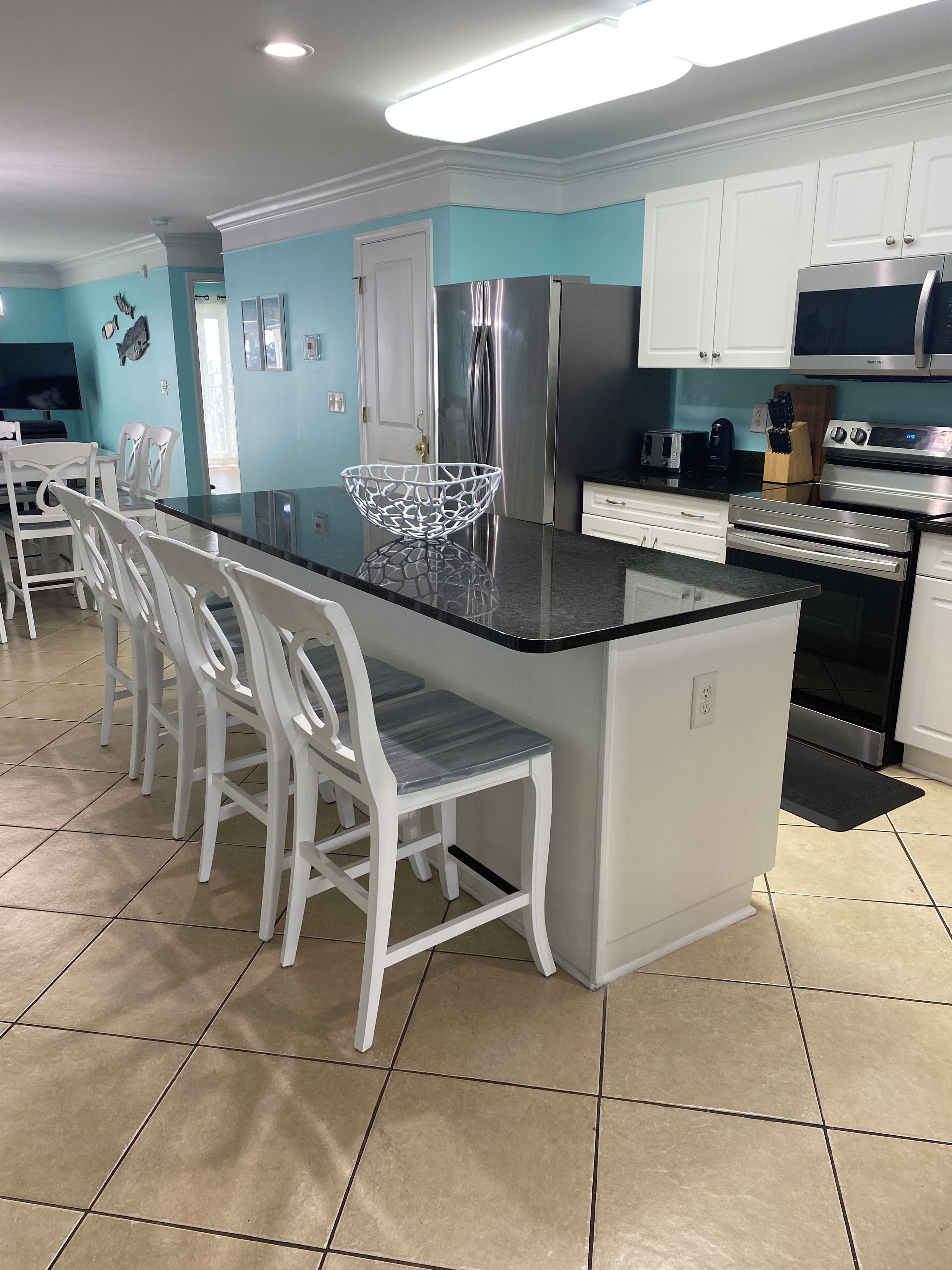 A modern kitchen with a central island, white cabinetry, and stainless steel appliances.