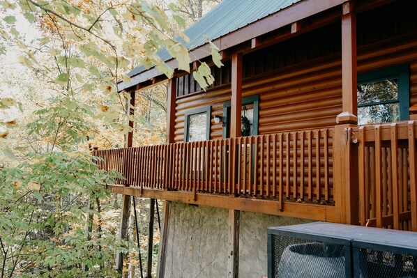 Una cabaña de madera con balcón, rodeada de árboles.