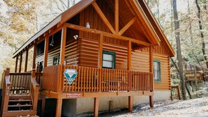 Eine Holzhütte mit Veranda, ein Schild, das angibt, dass sie zur Woodland Dream Kollektion gehört, und die Zahl '520' an der Geländer.