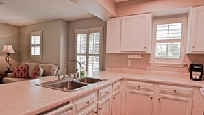 A kitchen with white cabinets, a double sink, and a window. - Sunseeker - Xanadu by Coastal Dreamin (Santa Rosa Beach)