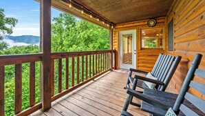 Eine Holzlaube mit Veranda, einer Uhr und zwei Schaukelstühlen.