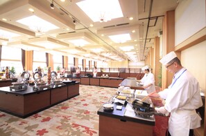A buffet setup in a spacious room with a high ceiling and large windows.