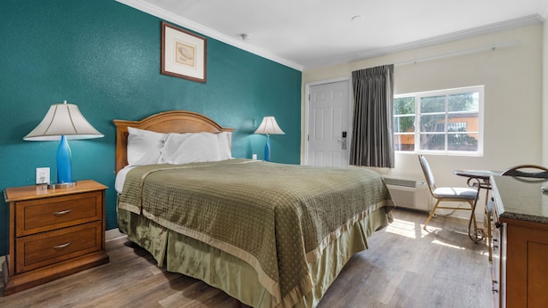 Une chambre à coucher comprenant un lit, des tables de chevet, une chaise, un bureau et une fenêtre.