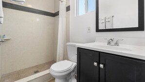 Une salle de bain équipée d’une douche, de toilettes, d’un lavabo et d’un miroir.