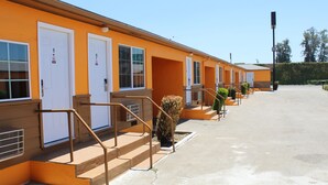 Une rangée de chambres de motel, chacune avec sa propre porte, un escalier extérieur et un ciel dégagé.