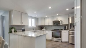 Una cocina moderna con armarios blancos, encimera de granito, electrodomésticos de acero inoxidable y una isla grande.