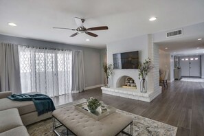 Cozy living space with a fireplace, high ceiling, and large window.