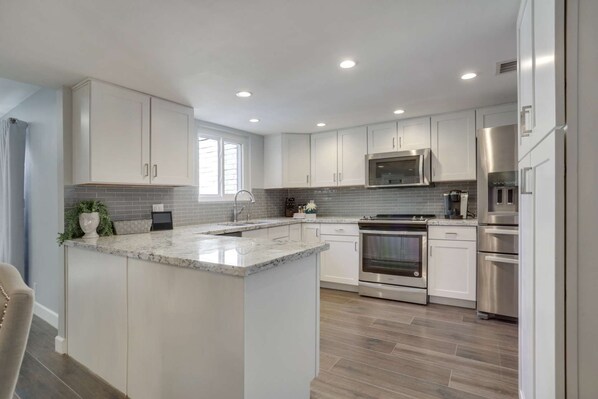 Features a central island with a sink, sleek cabinetry, and stainless steel appliances.