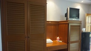 A wooden wardrobe with a television on top, a small table with a tissue box, and a mirror on the right. - Buppha Resort (Takua Pa)
