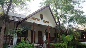 A traditional building with a wooden staircase leading to a porch, surrounded by lush greenery and trees. - Buppha Resort (Takua Pa)