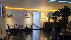 A lobby with two armchairs, a small table, a potted plant, and a lamp. - Gwangan Beach Blue Moon Motel (Busan)