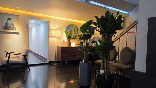 A lobby with a reception desk, a chair, a staircase, and potted plants. - Gwangan Beach Blue Moon Motel (Busan)