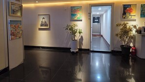 A hotel lobby with a polished floor, framed artwork on the walls, potted plants, and a CCTV sign. - Gwangan Beach Blue Moon Motel (Busan)