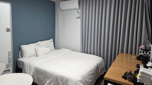 A hotel room with a bed, a desk with a telephone, headphones, and a towel. - Gwangan Beach Blue Moon Motel (Busan)