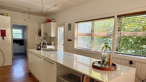 Eine moderne Küche mit einer zentralen Kochinsel, Barhocker und einem Fenster mit Jalousien.