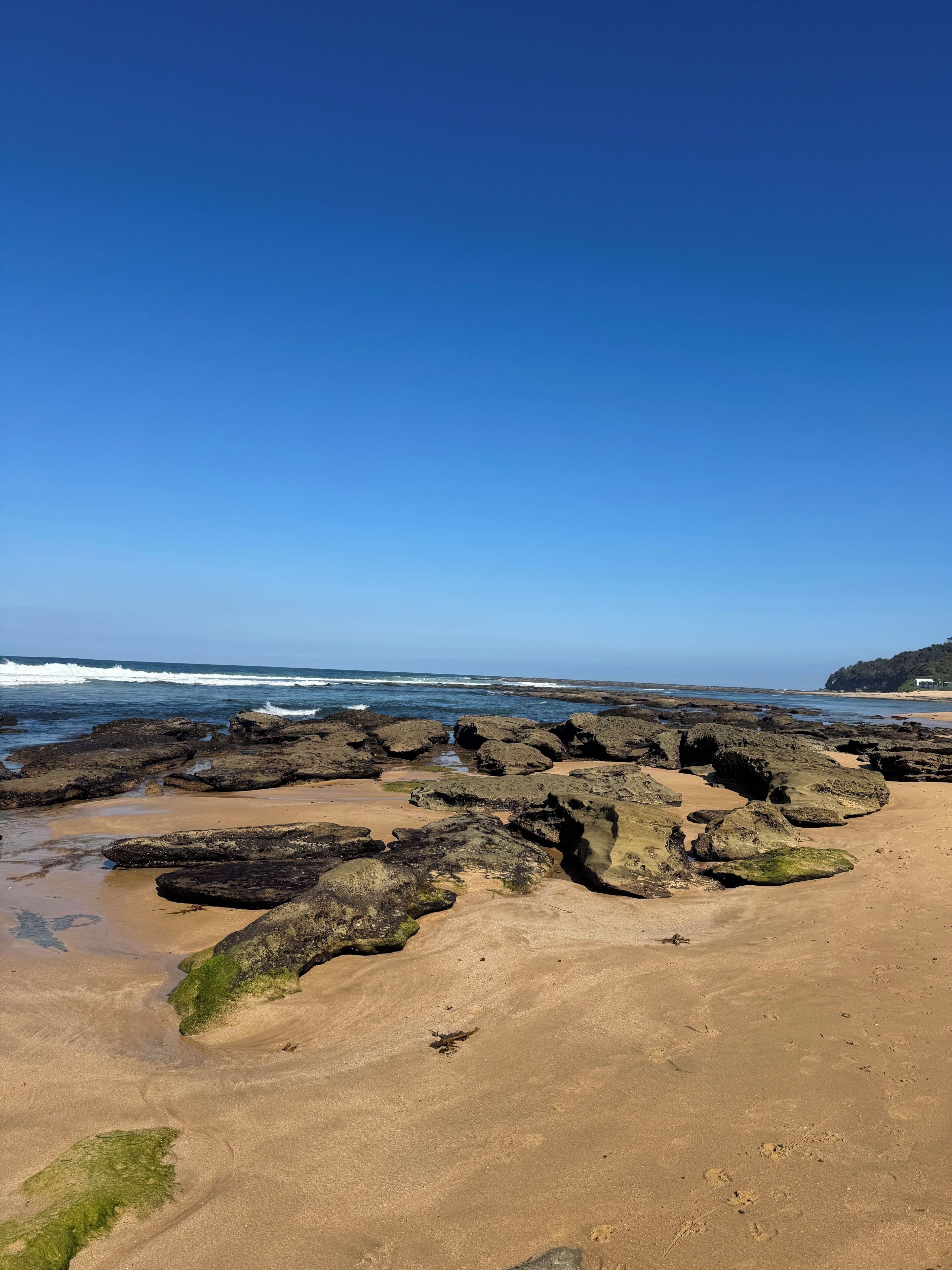 A beach with rocky terrain and a clear blue sky.