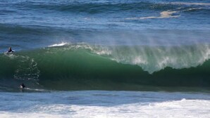 Eine große Welle im Ozean, auf der ein Surfer reitet.